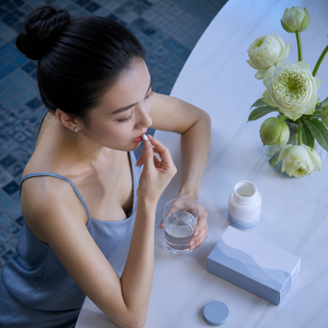 Người phụ nữ trẻ đang uống viên uống bổ sung làm đẹp da